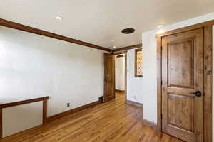 Unfurnished bedroom with wood finished floors, ornamental molding, and recessed lighting