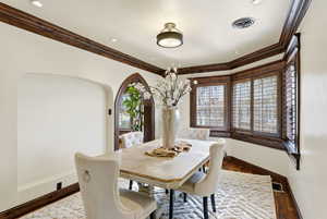 Dining room with wood finished floors, plenty of natural light, and ornamental molding