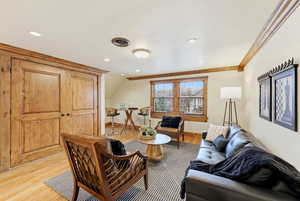 Living area with wood finished floors, lofted ceiling, recessed lighting, and ornamental molding