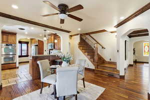 Dining room featuring arched walkways, a ceiling fan, recessed lighting, beam ceiling, and dark wood-style flooring