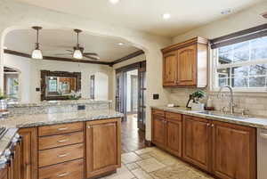 Kitchen with wood finish cabinetry, healthy amount of natural light, decorative light fixtures, and crown molding