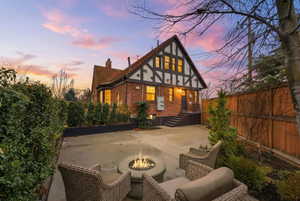 Rear view of property with brick siding, a chimney, a fire pit, a fenced backyard, and a patio area