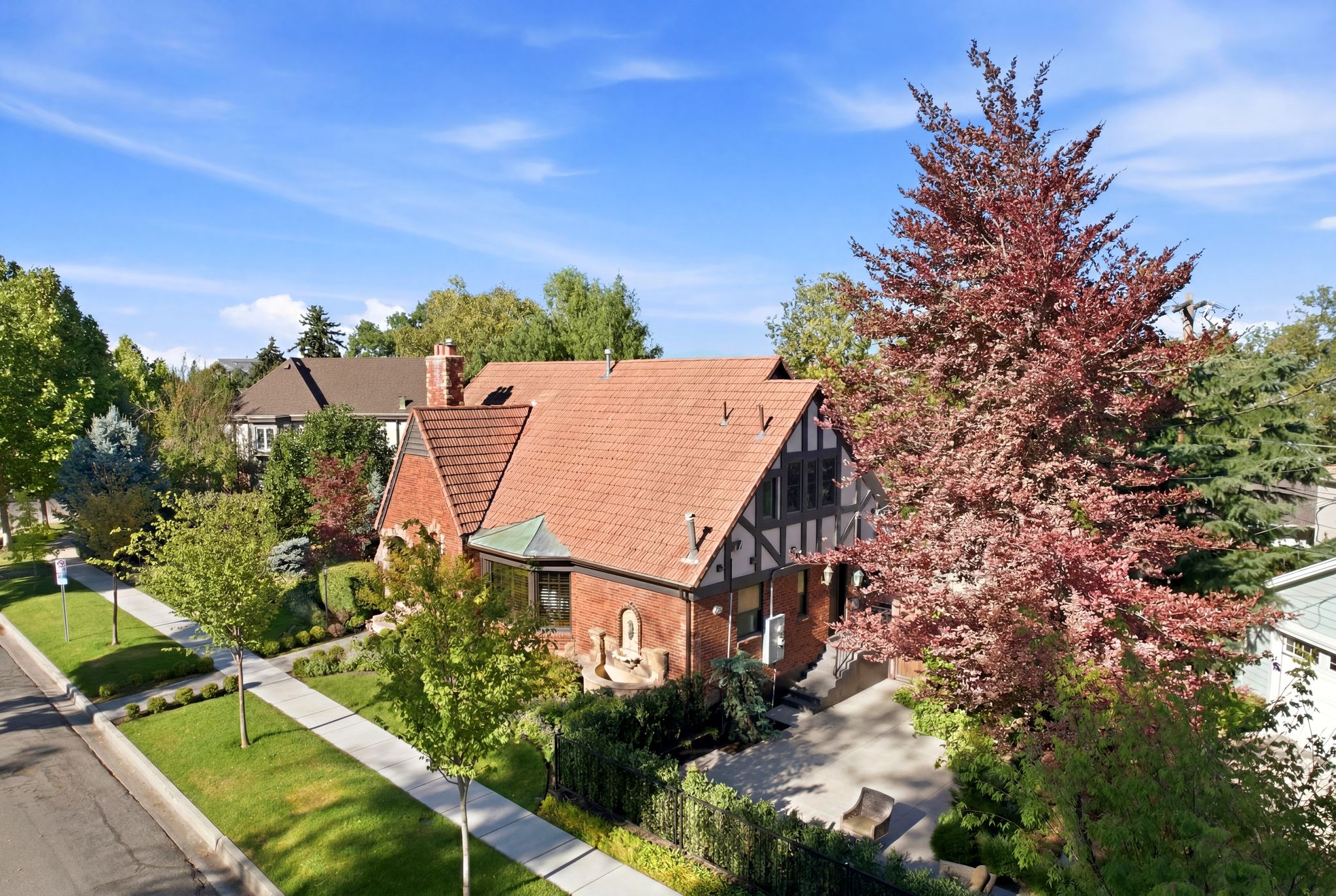 Tudor-style residence featuring a brick facade with half-timbering, a prominent chimney, and a terracotta tile roof