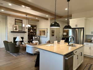 Kitchen featuring a breakfast bar area, white cabinetry, a kitchen island with sink, tasteful backsplash, and a fireplace