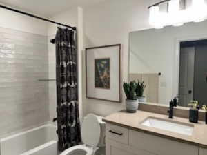 Full bathroom with shower / bath combo with shower curtain and vanity