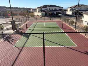 View of tennis court with a residential view