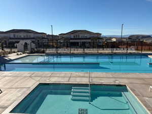 Community pool with a patio and an in-ground hot tub