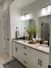 Bathroom featuring a shower stall, double vanity, and light tile patterned floors