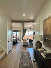 Living area with light wood-style floors, recessed lighting, and beam ceiling