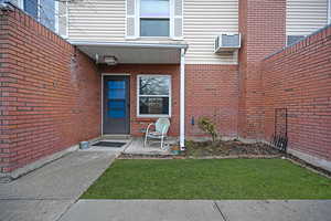 View of exterior entry with brick siding and a lawn