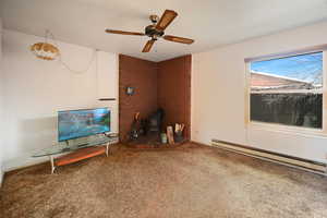 Unfurnished living room featuring baseboard heating, carpet flooring, and a ceiling fan