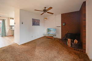 Living area featuring carpet, ceiling fan, a textured ceiling, and a wood stove