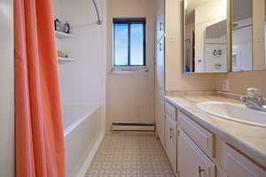 Bathroom with vanity, light floors, baseboard heating, and shower / bathtub combination with curtain