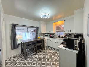 Kitchen featuring backsplash, white cabinets, stainless steel microwave, and light floors
