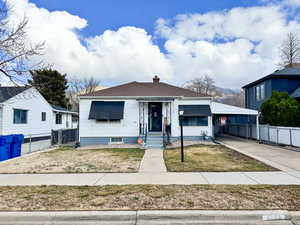 Bungalow featuring a chimney, a carport, and driveway