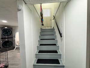 Stairs featuring stacked washer and dryer and wood finished floors