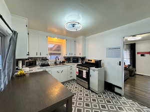 Kitchen featuring white cabinetry, stainless steel appliances, tasteful backsplash, and light countertops