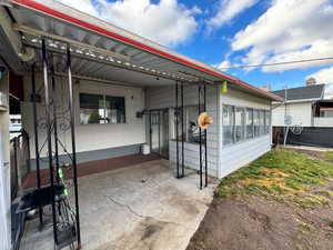 View of front of property featuring a patio area, concrete block siding, and a sunroom