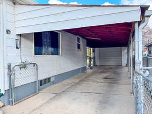 View of side of property featuring an attached carport, a gate, and driveway