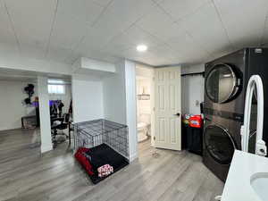 Laundry area with stacked washer and dryer and light wood-style flooring