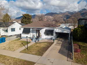 View of front of property featuring a chimney, a front lawn, a carport, a mountain view, and driveway
