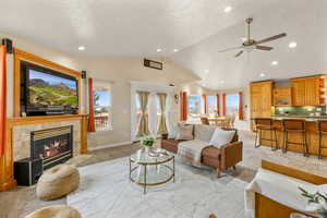 Living area with a tile fireplace, a ceiling fan, light colored carpet, a high textured ceiling, and recessed lighting