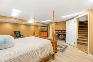 Bedroom with a glass covered fireplace and wood finished floors