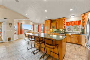 Kitchen featuring a center island, wood finish cabinetry, open shelves, a kitchen breakfast bar, and recessed lighting