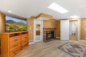Living area with light wood-style flooring, a fireplace with flush hearth, and a textured ceiling
