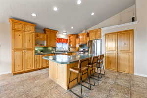 Kitchen with recessed lighting, a kitchen island, a kitchen breakfast bar, light stone finish floors, and stainless steel appliances