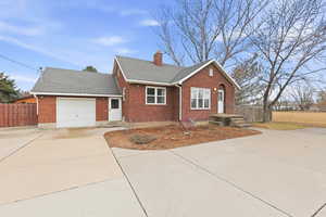 View of front facade with concrete driveway, brick siding, roof with shingles, a chimney, and a garage