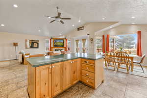 Kitchen with ceiling fan, a center island, recessed lighting, dark countertops, and a textured ceiling