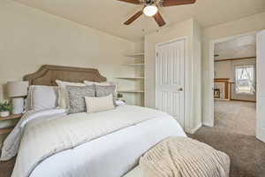Carpeted bedroom with a textured ceiling, a tile fireplace, and a ceiling fan