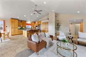 Living room with a ceiling fan, lofted ceiling, recessed lighting, and light stone finish floors