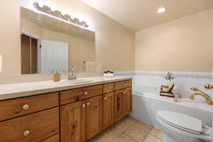 Full bathroom featuring vanity, a bath, a textured ceiling, light tile patterned flooring, and recessed lighting