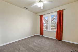 Empty room with carpet, a textured ceiling, and a ceiling fan