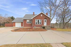 View of front facade with brick siding, a chimney, driveway, a garage, and roof with shingles