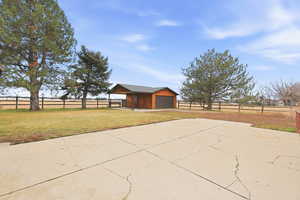 View of patio with an outdoor structure, a detached garage, and concrete driveway