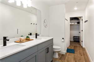 Bathroom featuring double vanity, light wood-style floors, and curtained shower