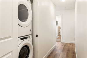 Laundry area with light wood-type flooring and stacked washer / dryer