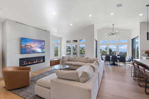Living area featuring a glass covered fireplace, recessed lighting, light wood-style floors, and lofted ceiling