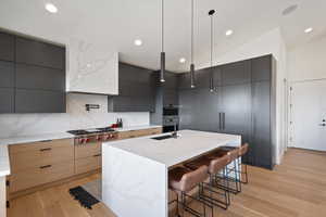 Dual tone kitchen with a kitchen bar, modern cabinets, an island with sink, vaulted ceiling, and dual tone cabinetry