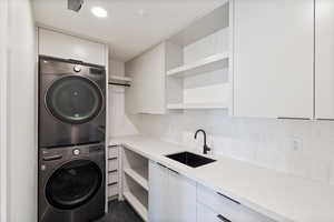Laundry room featuring stacked washer and dryer and a sink