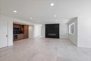 Unfurnished living room with recessed lighting, wet bar, a fireplace, and wine cooler