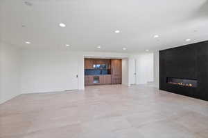 Unfurnished living room with wet bar, wine cooler, recessed lighting, and a large fireplace