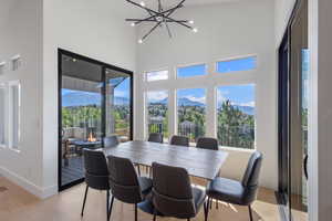 Dining space featuring a mountain view, a chandelier, light wood-style flooring, healthy amount of natural light, and a high ceiling