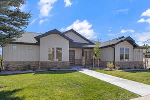 View of front of property featuring board and batten siding, a front lawn, and a shingled roof