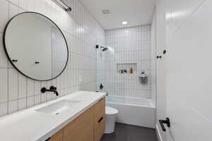 Bathroom featuring shower / bathtub combination, vanity, tile walls, recessed lighting, and dark tile patterned floors