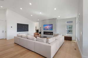 Living room featuring light wood-type flooring, recessed lighting, a fireplace, and vaulted ceiling