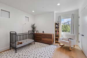 Bedroom with a crib, recessed lighting, wood finished floors, and a closet